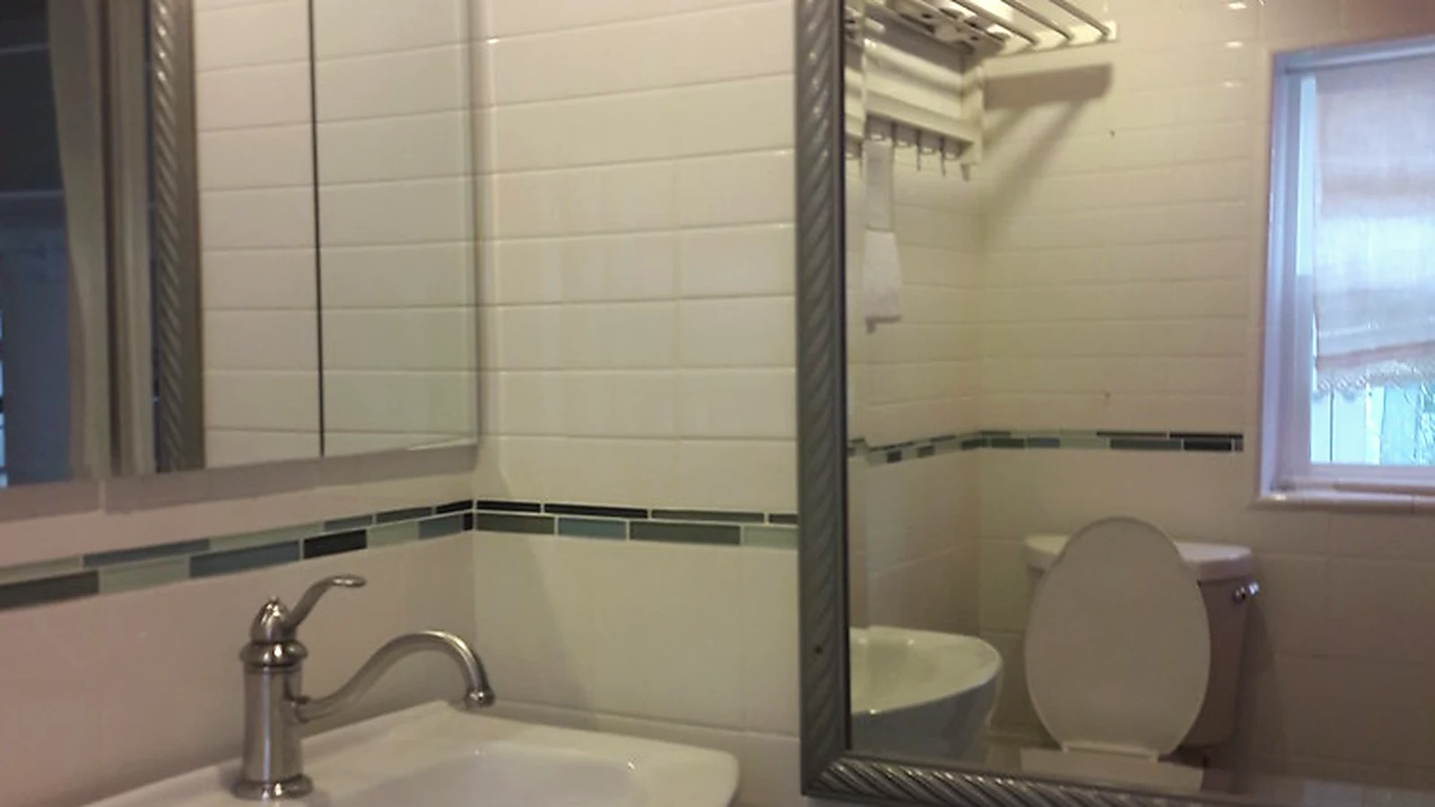 Bathroom wall finishes showing newly tiled walls, basin and fitted mirror