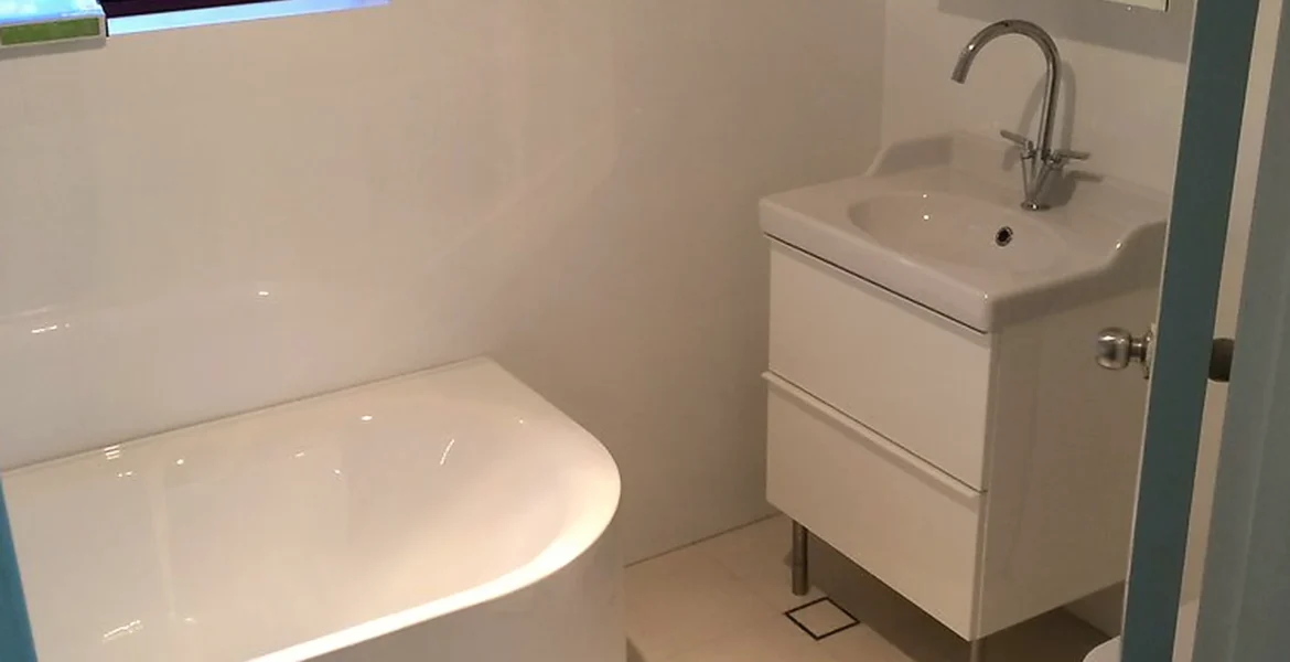 Compact ensuite bathroom renovation with bath, vanity unit and fitted mirror