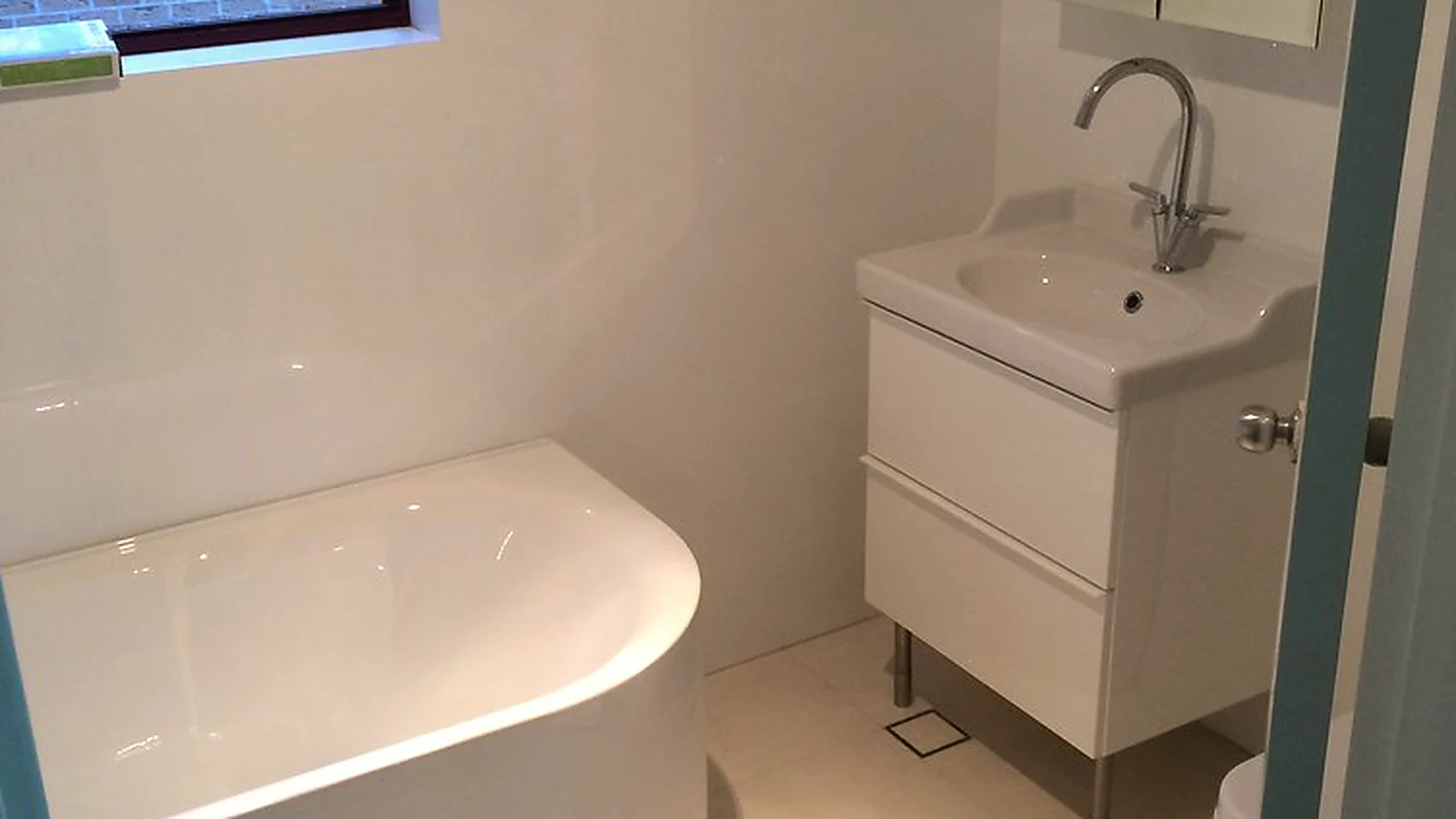 Compact ensuite bathroom renovation with bath, vanity unit and fitted mirror